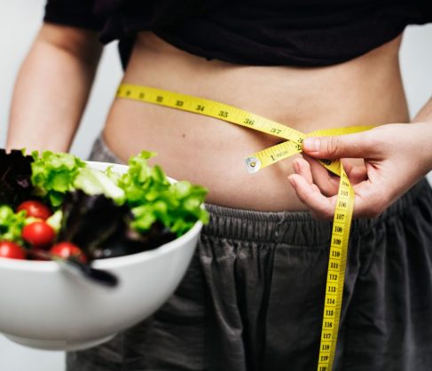 person-measuring-waist-holding-a-bowl-of-salad